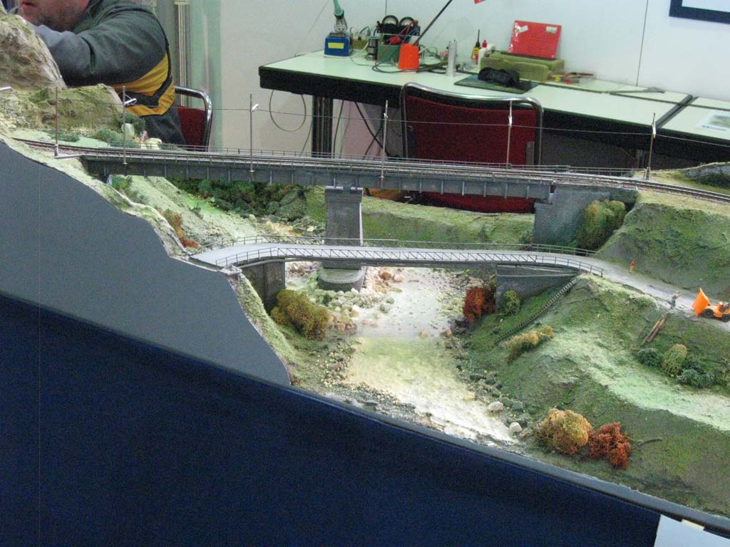 En primer plano la maqueta, al fondo las herramientas y en medio haciendo trabajo en la feria