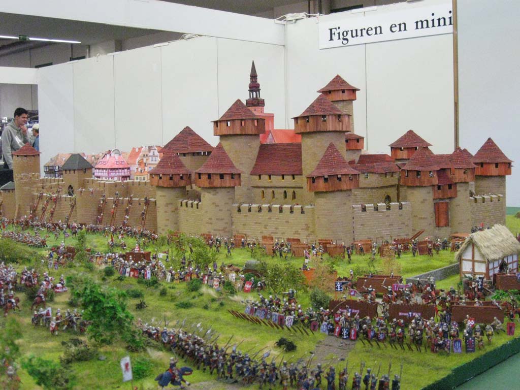 Castillo medieval y figuras en miniatura representando el asedio con catapultas