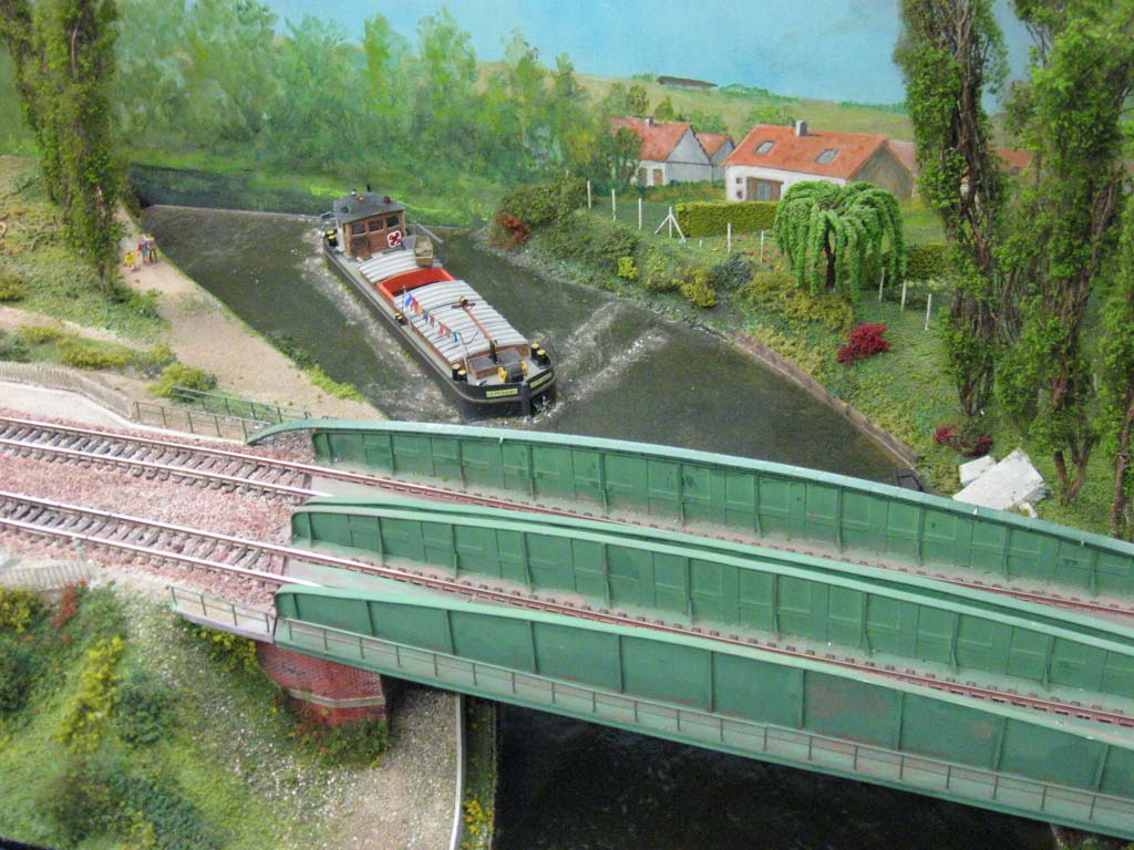 Canal con barcaza cruzando bajo las vías del tren